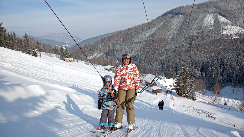 Skilifte Feistritzsattel, © Wiener Alpen, Foto: Franz Zwickl Zwei Skifahrer auf einem Schlepplift in einer verschneiten Berglandschaft.