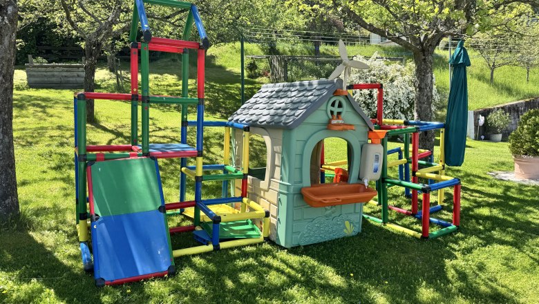 Ferienwohnung Koglhof, © Andrea Tauchner/Koglhof Ein bunter Spielplatz mit Klettergerüst und Spielhaus im Garten.