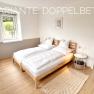 Schlafzimmer, © Christoph Menhofer Modernes Schlafzimmer mit Doppelbett, Holzboden und Fenster mit Blick nach draußen.