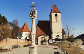 Pfarrkirche Unter-Aspang, © Wiener Alpen Pfarrkirche Unter-Aspang mit Säule im Vordergrund und blauem Himmel.