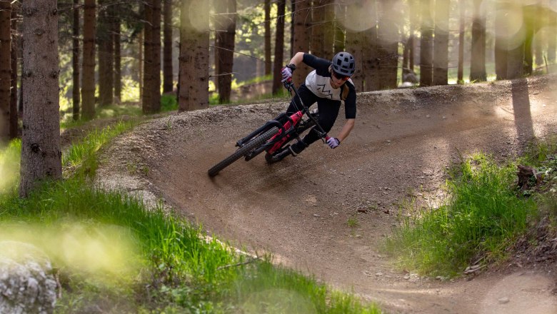 Wexl Trails, © Wexl Trails Mountainbiker fährt durch einen Wald auf einem kurvigen Trail.