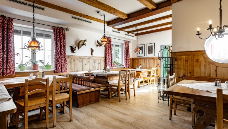 Alpengasthof Enzian, © Alpengasthof Enzian/Thomas Gobauer Gemütlicher Gastraum mit Holzmöbeln und roten Vorhängen.