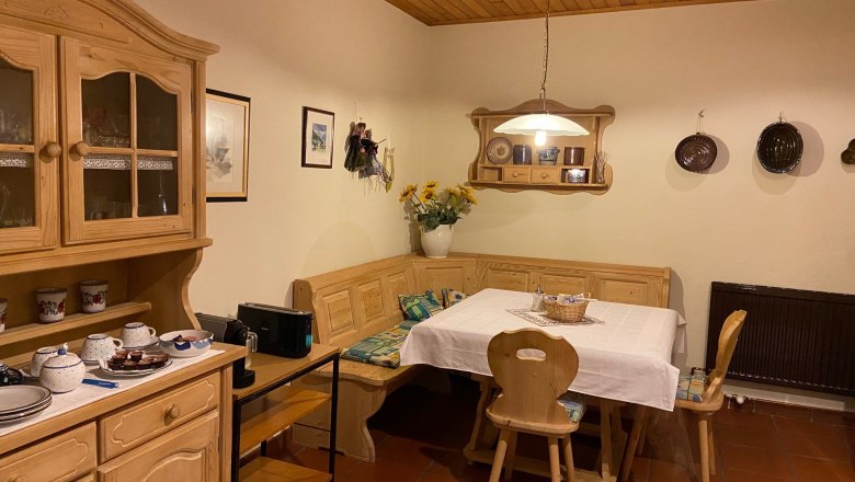 Küche für Gäste nutzbar, © Wiener Alpen Gemütliche Küche mit Holzmöbeln, Esstisch und Eckbank, dekoriert mit Geschirr und Blumen.