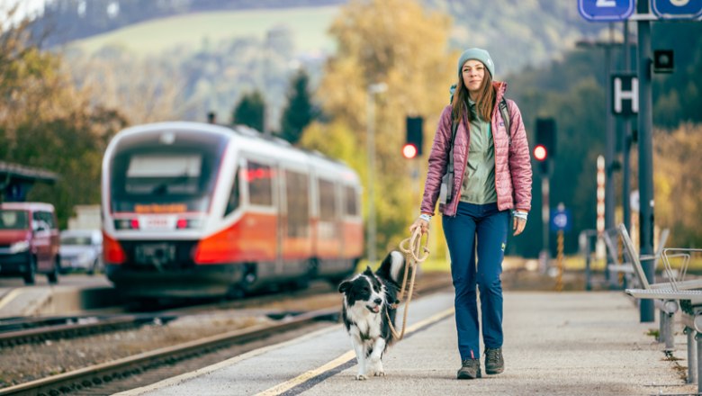 Bahnhof Aspang, © Wiener Alpen, Kremsl Frau mit Hund am Bahnhof Aspang, Zug im Hintergrund.
