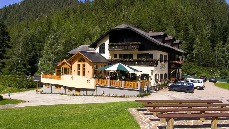 Alpengasthof Kummerbauerstadl, © Kummerbauerstadl, Foto Verlag Fasch Alpengasthof Kummerbauerstadl in den Bergen mit Terrasse und Autos.
