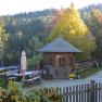 Kronaushof, © Erika Kronaus Ländlicher Hof mit Holzhütte, Holzbank, Holzzaun und grauem Auto, im Hintergrund ein Wald.