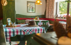 Gaststube, © Wiener Alpen / Christian Kremsl Gemütliche Gaststube mit karierten Tischdecken und einem Hut auf dem Tisch.