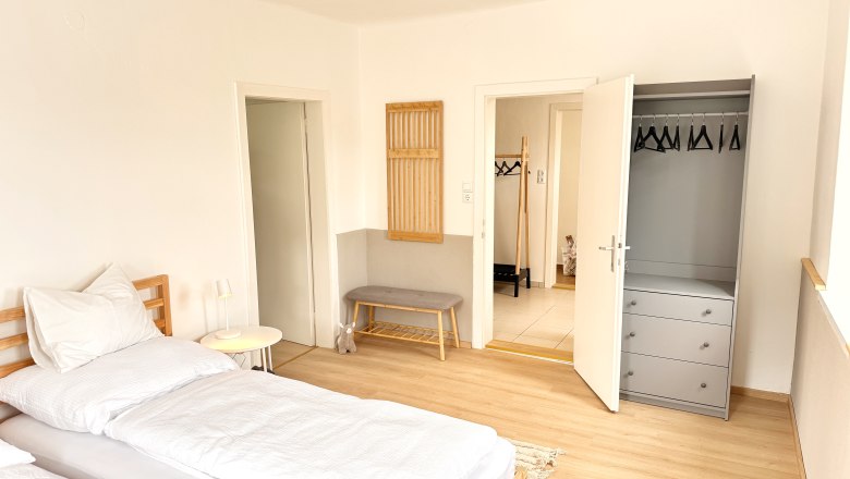 Schlafzimmer, © Christoph Menhofer Helles Schlafzimmer mit Bett, Kleiderschrank und Bank.