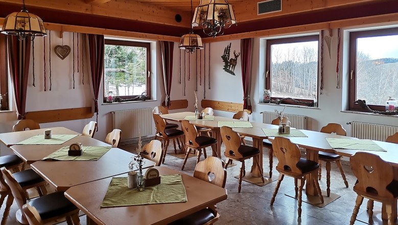 Gemütliche Gaststube, © Wiener Alpen Gemütliche Gaststube mit Holzmöbeln und grünen Tischdecken, großen Fenstern und rustikaler Dekoration.
