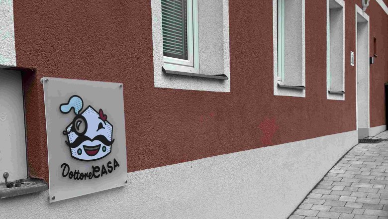 Dottore Casa Aussenansicht, © Michael Liska Außenansicht eines Gebäudes mit roter Fassade und einem Schild mit der Aufschrift 'Dottore Casa'.