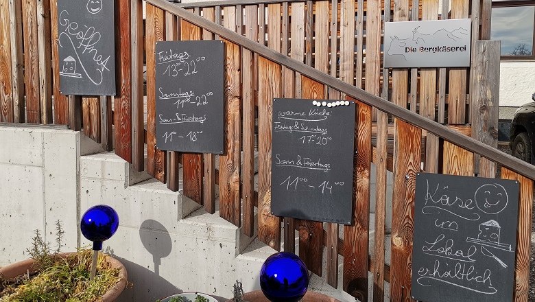 Eingang zur Bergkäserei mit Schildern und blauen Kugeln.