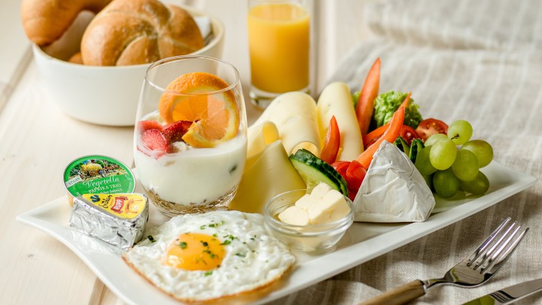 Ein Teller mit vegetarischem Fr&uuml;hst&uuml;ck: Spiegelei, K&auml;se, Gem&uuml;se, Joghurt mit Obst, Br&ouml;tchen und Orangensaft.
