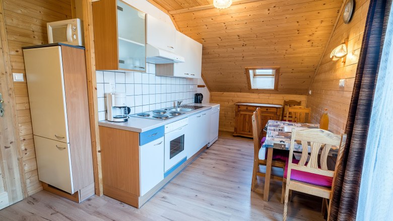 Küche mit Holzverkleidung, Esstisch und Küchenzeile.