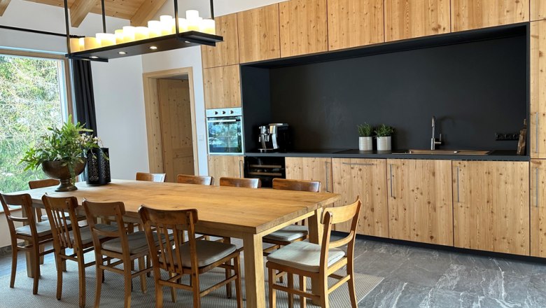Moderne Küche mit Holzmöbeln und großem Esstisch.