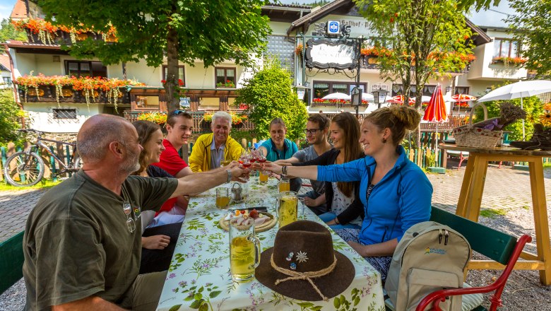 Gruppe von Menschen stößt in einem Gastgarten an.