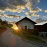 Ein Haus auf einem H&uuml;gel bei Sonnenuntergang mit einer kurvigen Stra&szlig;e im Vordergrund.