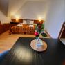Ein gemütliches Doppelzimmer mit einem dekorierten Tisch im Vordergrund und einem Bett im Hintergrund.