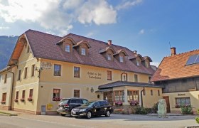 Ein traditionelles Gasthaus mit Bäckerei und geparkten Autos davor.