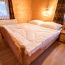 Gemütliches Schlafzimmer mit Holzwänden, Doppelbett und Nachttisch in einer Ferienwohnung.