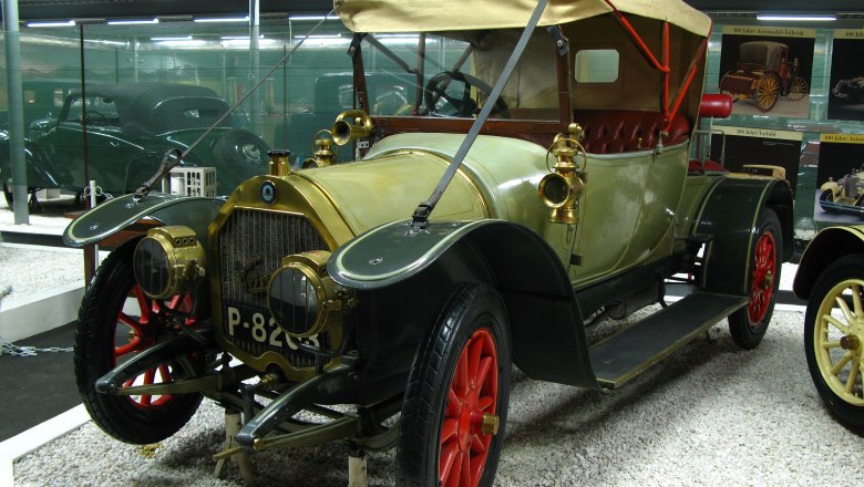 Ein Oldtimer mit rotem Verdeck und roten R&auml;dern in einem Automobilmuseum.
