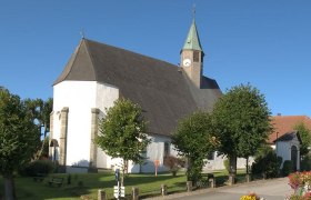 Wallfahrtskirche Maria Namen mit Turm und Bäumen im Vordergrund.