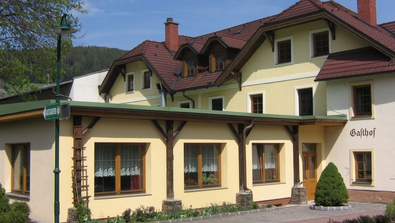 Ein traditioneller Gasthof mit gelber Fassade und roten Dachziegeln.