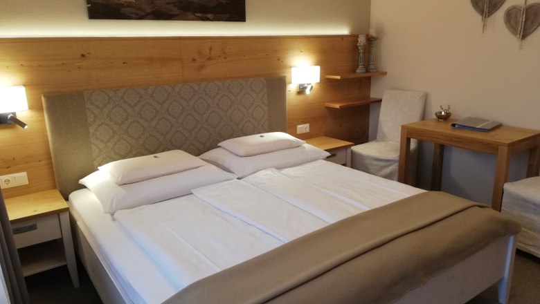 Gemütliches Hotelzimmer mit Doppelbett, Holzmöbeln und Wanddekoration.