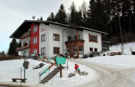 Winterliches Gästehaus Apschner mit Schnee und Wald im Hintergrund.