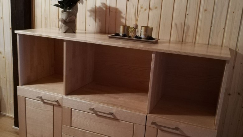 Holzkommode mit Dekoration in einem Raum mit Holzvertäfelung.