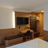 Modern eingerichtetes Hotelzimmer mit Holzm&ouml;beln, einem Schreibtisch, einem Fernseher und einem Kleiderschrank.