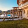 Außenbereich des Naturhotel Molzbachhof mit Pool und Liegestühlen bei Sonnenuntergang.