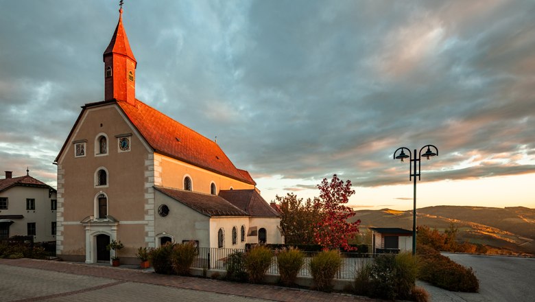 Kirche in St. Corona am Wechsel bei Sonnenuntergang mit bew&ouml;lktem Himmel.