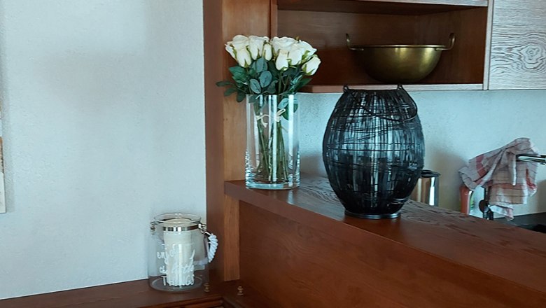 Holzküche mit Regalen, Kissen und Dekorationen.