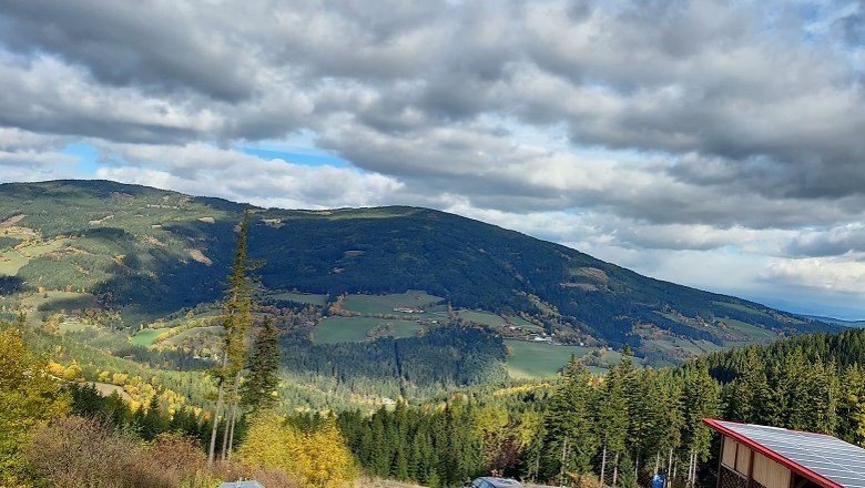 Panoramablick auf eine h&uuml;gelige Landschaft mit W&auml;ldern und Feldern unter einem bew&ouml;lkten Himmel.