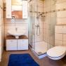 Modernes Badezimmer mit Dusche, Waschbecken, WC und blauer Badematte.
