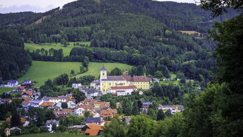 Landschaft mit Kirche und Kloster in einem Dorf, umgeben von W&auml;ldern und H&uuml;geln.