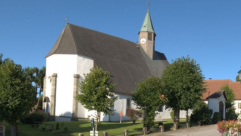 Wallfahrtskirche Maria Namen mit Turm und Bäumen im Vordergrund.