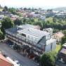 Luftaufnahme eines Hotels mit Solarpanelen auf dem Dach, umgeben von B&auml;umen und weiteren Geb&auml;uden in einer l&auml;ndlichen Gegend.