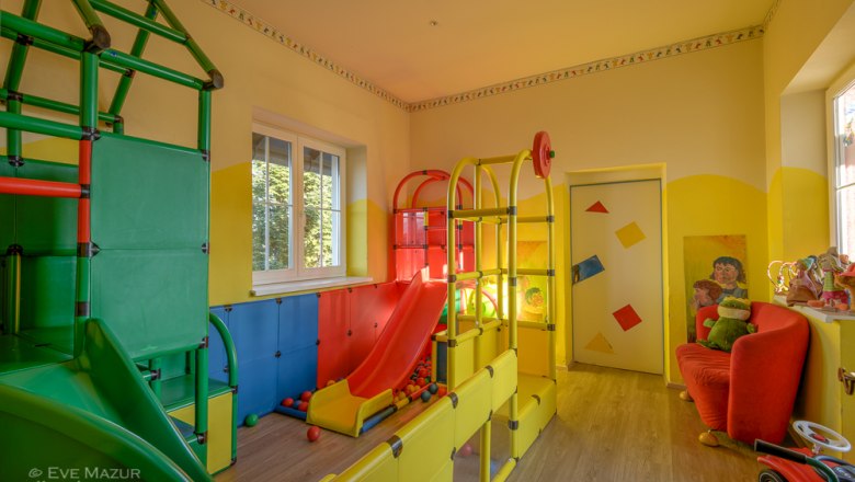Buntes Kinderspielzimmer mit Rutsche und Klettergerüst.