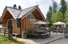 Holzhütte mit Terrasse und Sonnenschirmen im Freien.