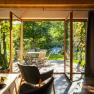 Blick aus einem Wohnzimmer auf eine Terrasse mit Gartenmöbeln und grünem Garten.