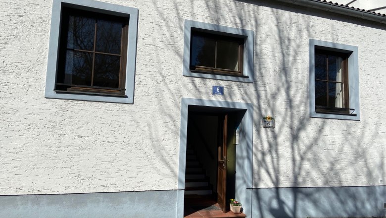 Eingang eines weißen Gebäudes mit blauen Fensterrahmen und Türrahmen.