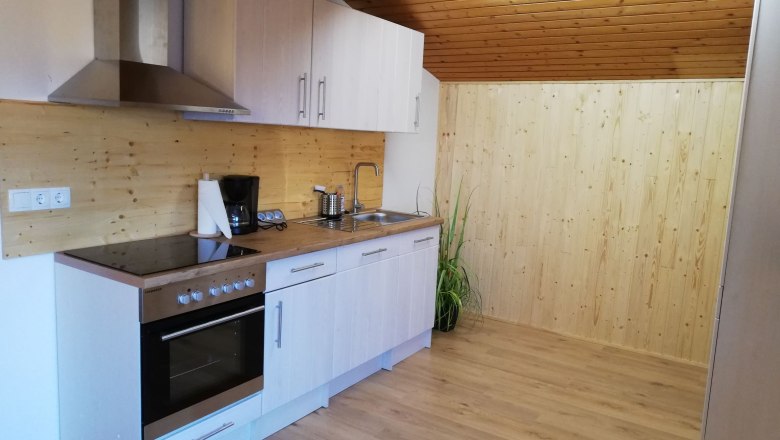 Moderne Küche in einem Dachgeschoss mit Holzverkleidung und Geräten.