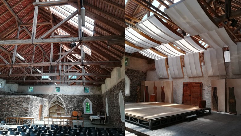 Innenansicht eines historischen Gebäudes mit Holzdach und Bühne.