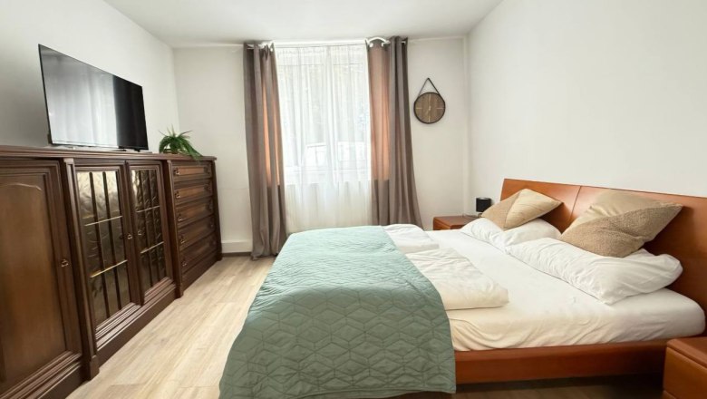 Ein gem&uuml;tliches Schlafzimmer mit einem gro&szlig;en Bett, Holzm&ouml;beln und einem Fernseher an der Wand.