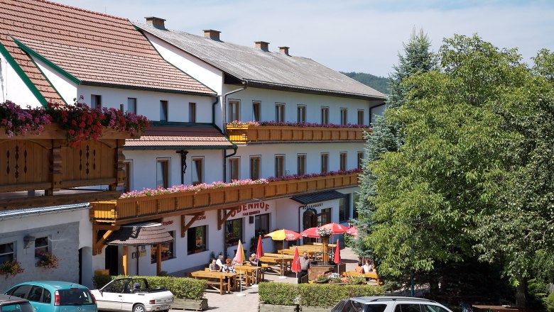 Gasthof-Pension &Ouml;denhof mit Terrasse und geparkten Autos.
