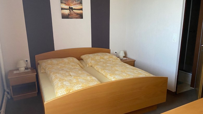 Ein Doppelzimmer mit einem Holzbett, zwei Nachttischen und einem Bild an der Wand.