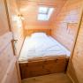Kleines Kinderzimmer mit Holzverkleidung, Einzelbett und Dachfenster.