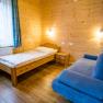 Kinderzimmer mit Holzwänden, Einzelbett, blauem Sofa und Nachttisch.