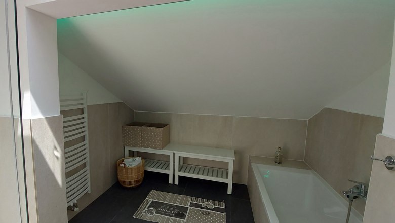 Modernes Badezimmer mit Badewanne, Dachschräge, Handtuchhalter und Dekoration.